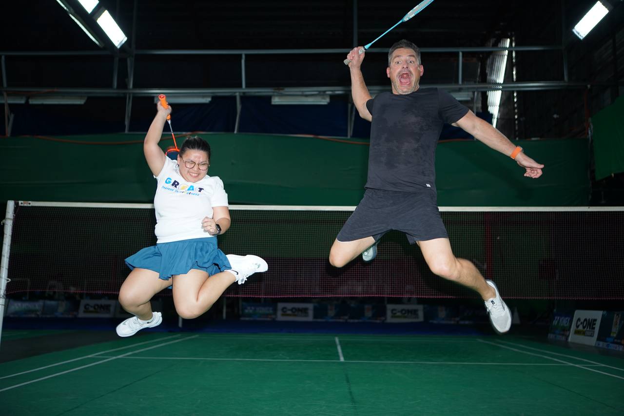 Brad Stevens jumping mid-air with OA team member at badminton tournament