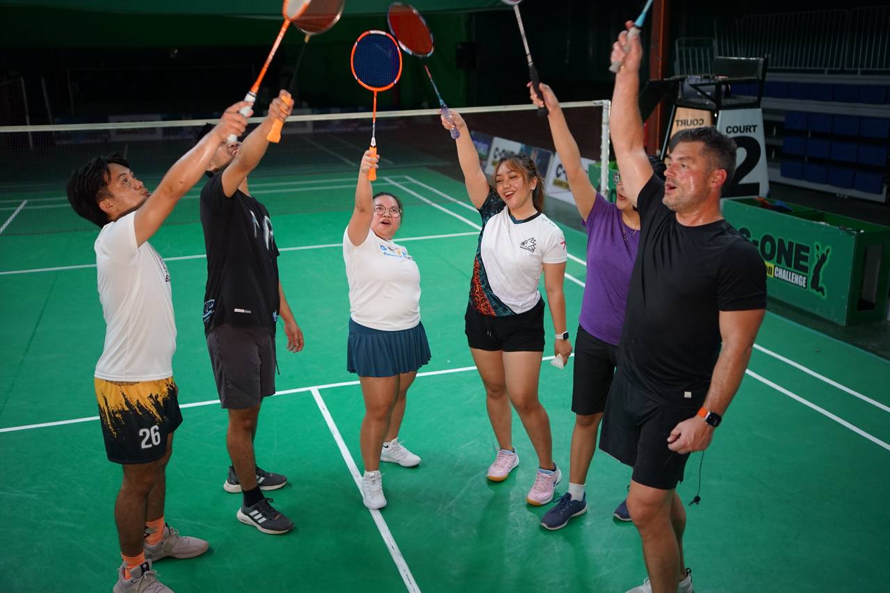 Brad and OA team raising rackets together after badminton match